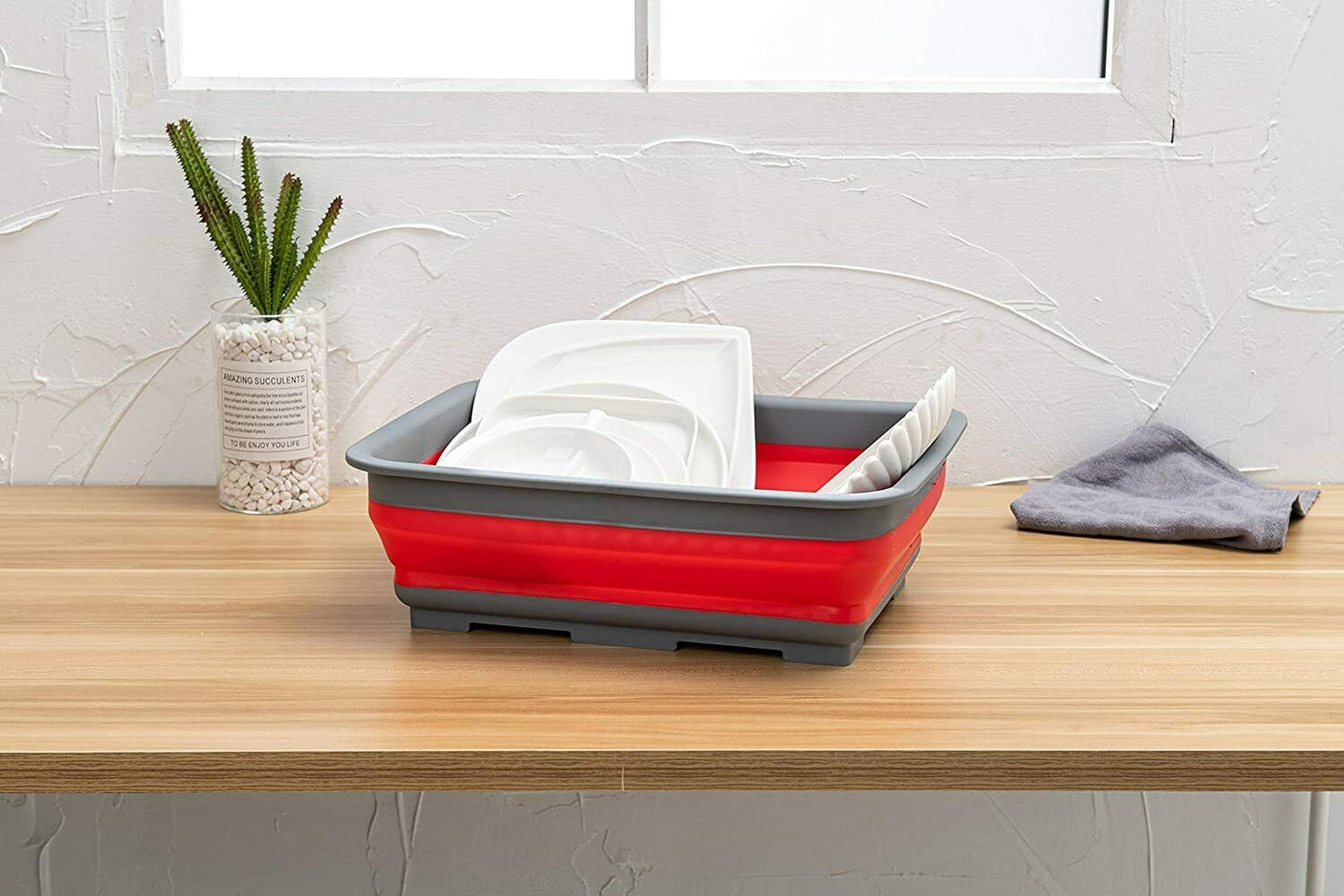 Red collapsible dish drainer with white plates inside