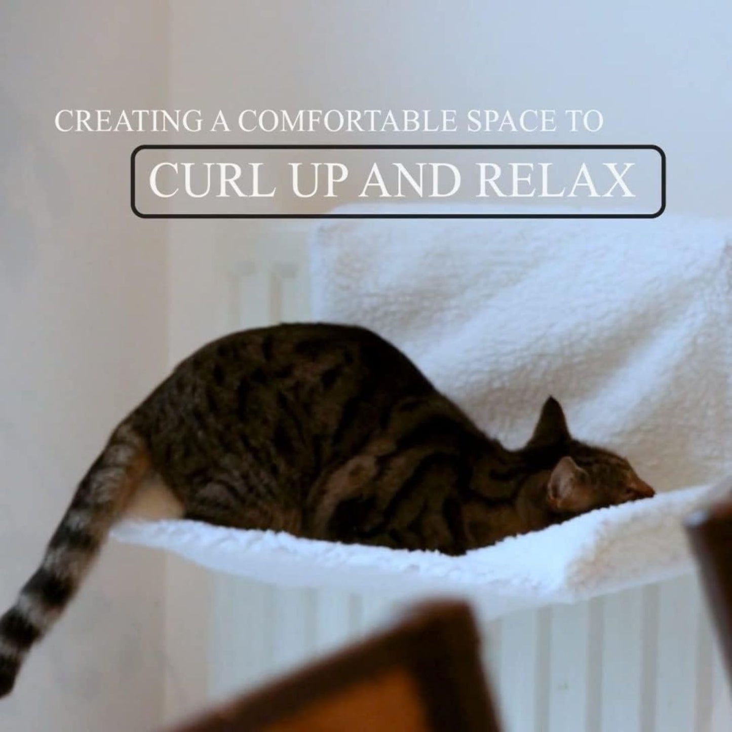 Cat curled up on white fleece radiator hammock bed with cozy winter vibe