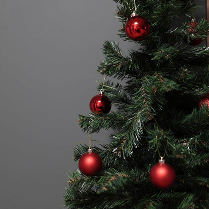 Close-up of a Christmas tree with red ornaments against a gray background