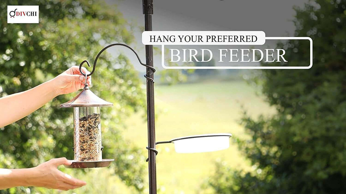 Hand placing a bird seed feeder onto hook of metal bird feeding station