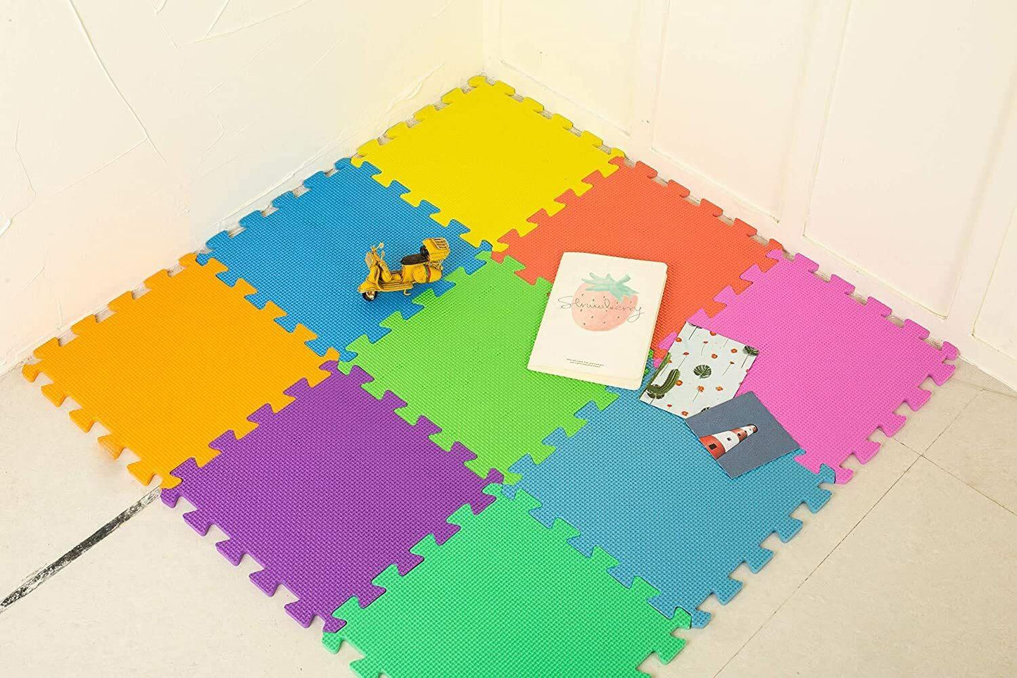 Bright foam play mat placed in a room corner with toys and books on top