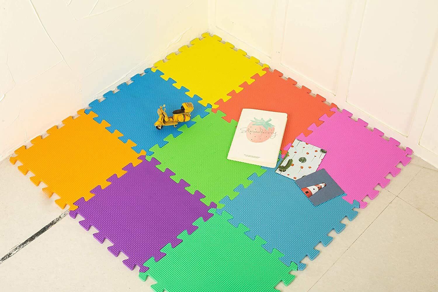 Bright foam play mat placed in a room corner with toys and books on top