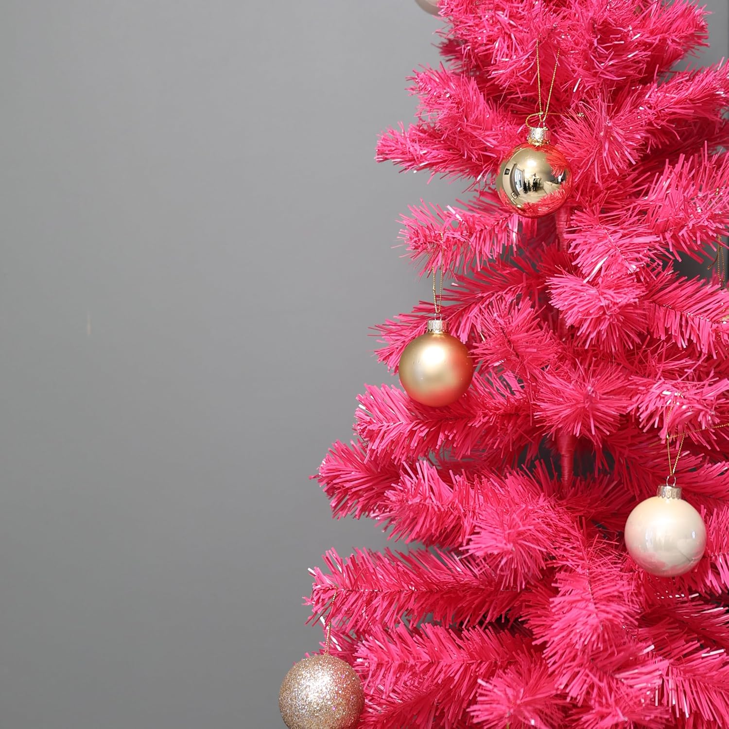 Pink Christmas tree with gold ornaments on a gray background