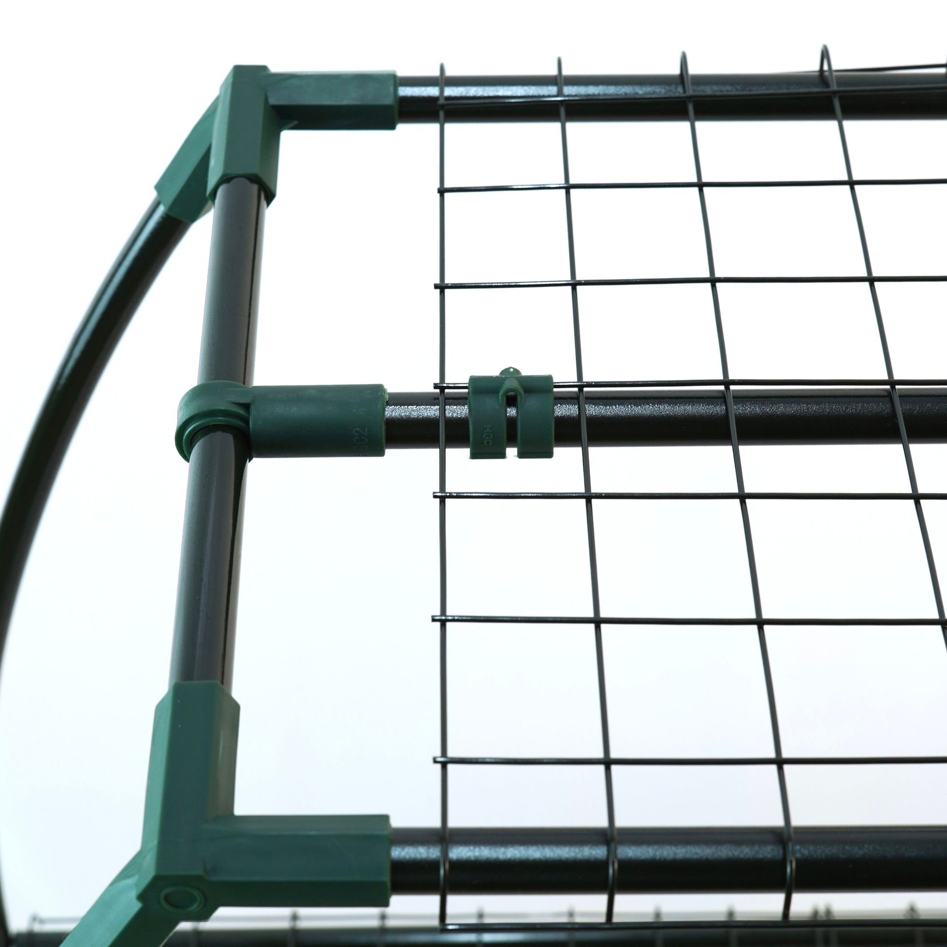 Close-up of a green metal gate with wire mesh on a white background